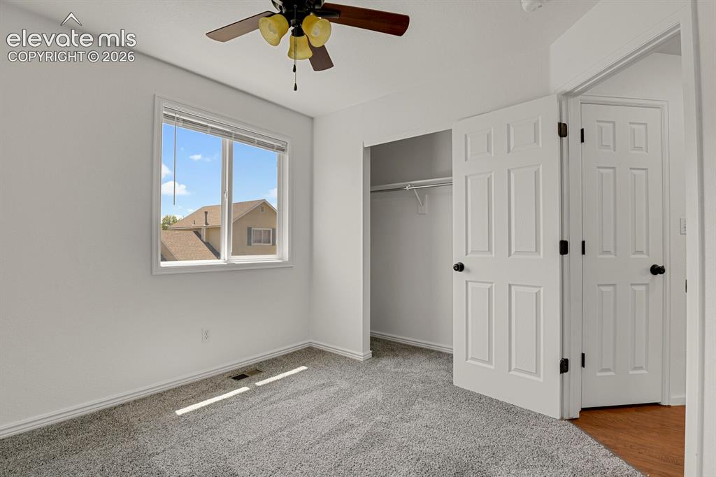 Image 34 of 49: Bedroom with light gray carpeting, neutral white walls, and a multi-pane wi
