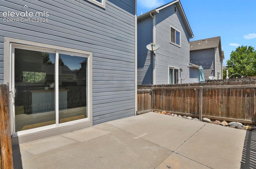 Image 37 of 49: Private outdoor patio space featuring a concrete surface and wood fencing