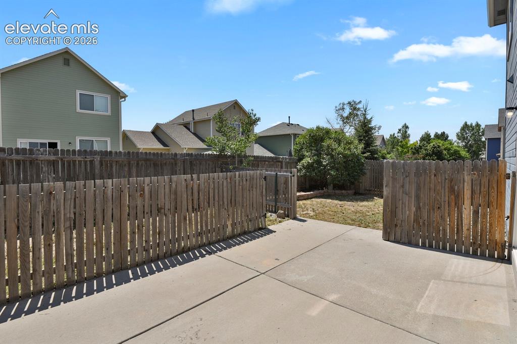 Image 38 of 49: Concrete patio area featuring a wooden privacy fence and a rear gate