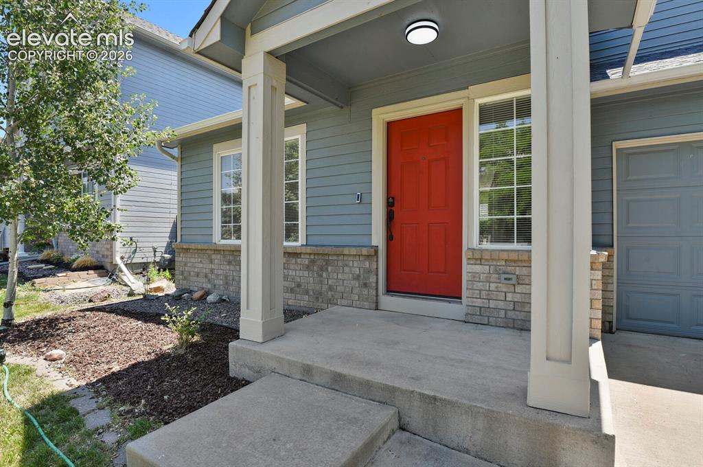 Image 4 of 49: Inviting front entry featuring a bold red door, transom window, and a cover