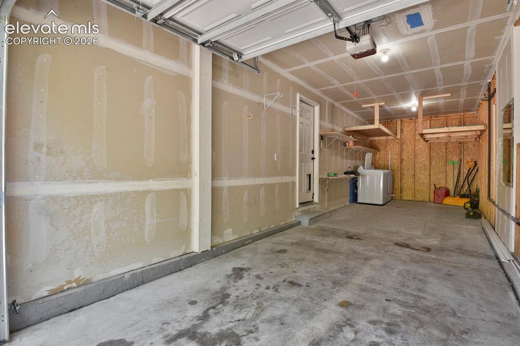 Image 42 of 49: Spacious garage featuring a concrete floor, overhead garage door, built-in