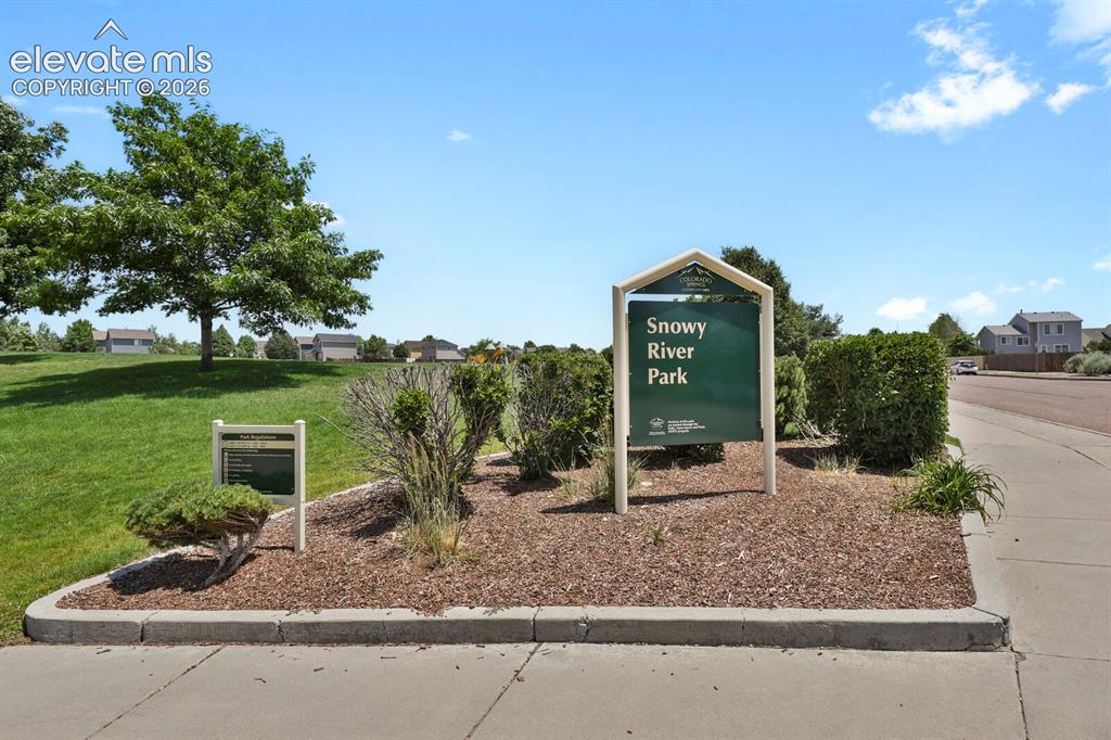 Image 43 of 49: Community park entrance featuring manicured landscaping, established trees,