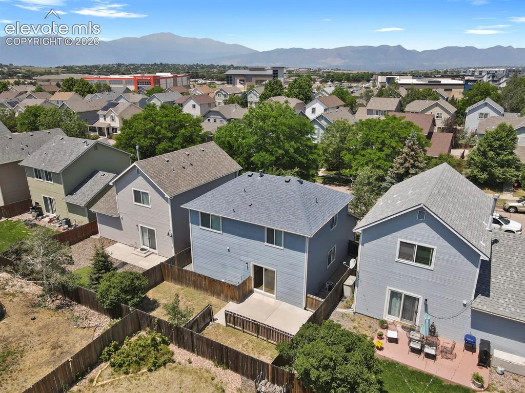 Image 46 of 49: Rear exterior of a light blue two-story residence featuring a private fence