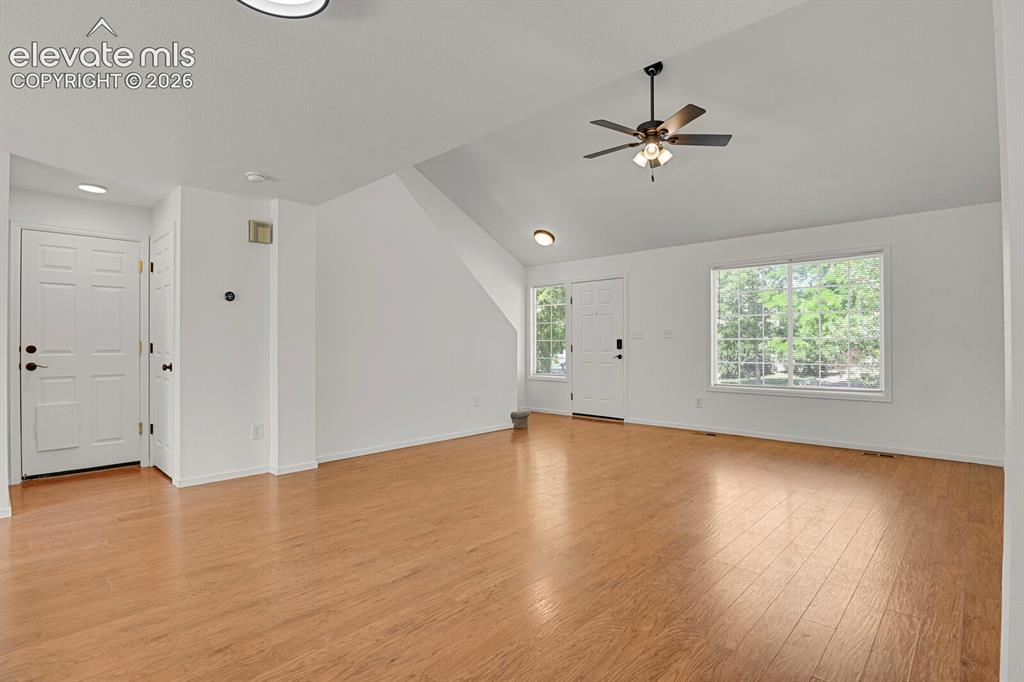 Image 9 of 49: Spacious living area featuring vaulted ceilings, wood-finish flooring, a ce