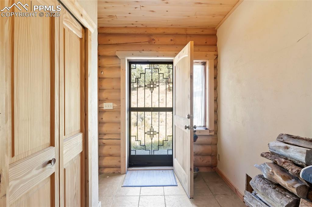 Image 12 of 33: Tiled entryway featuring wooden ceiling and rustic walls