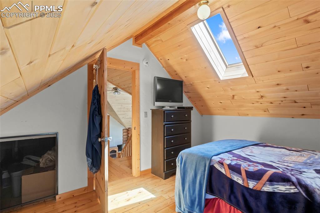 Image 17 of 33: Bedroom featuring a skylight, light wood finished floors, and wooden ceilin