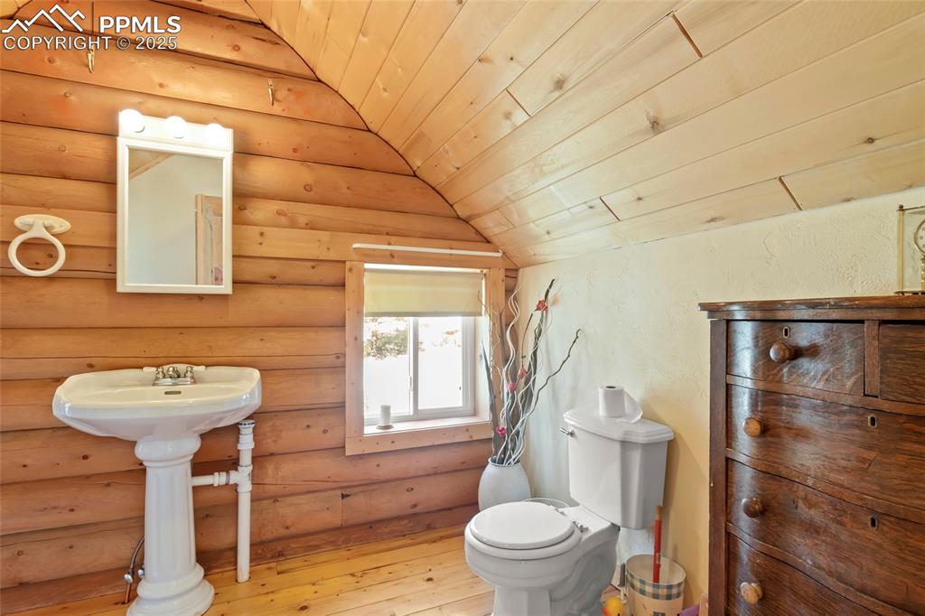 Image 19 of 33: Bathroom with hardwood / wood-style floors, log walls, wooden ceiling, and 