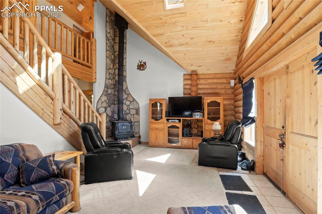 Image 2 of 33: Living area featuring a wood stove, high vaulted ceiling, wood ceiling, lig