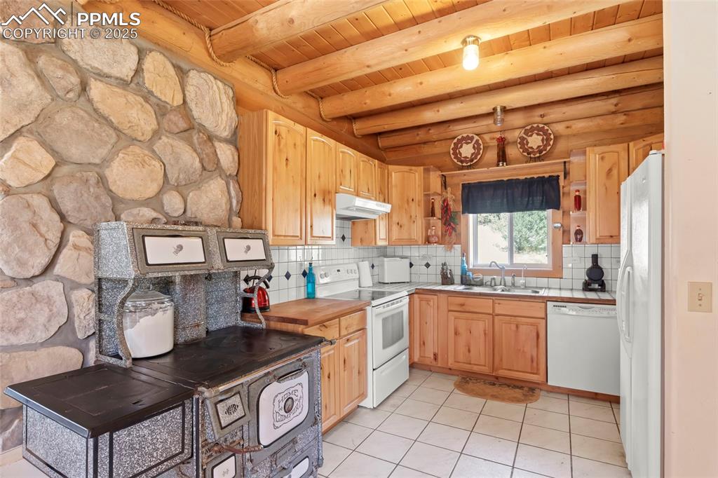 Image 5 of 33: Kitchen featuring light tile patterned floors, white appliances, backsplash