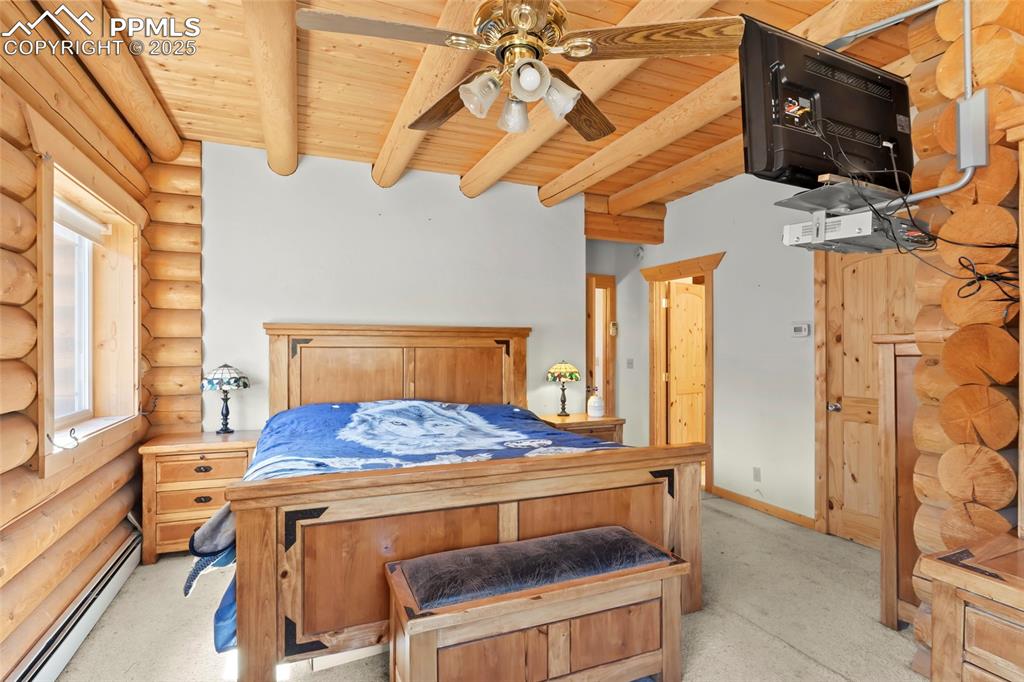 Image 7 of 33: Bedroom featuring a baseboard radiator, rustic walls, and a wooden ceiling 