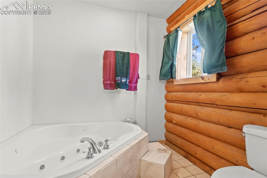 Image 9 of 33: Full bath with a whirlpool tub and light tile patterned floors