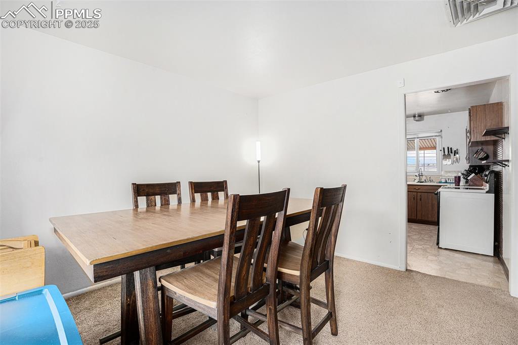Image 11 of 30: Dining space featuring light colored carpet and baseboards