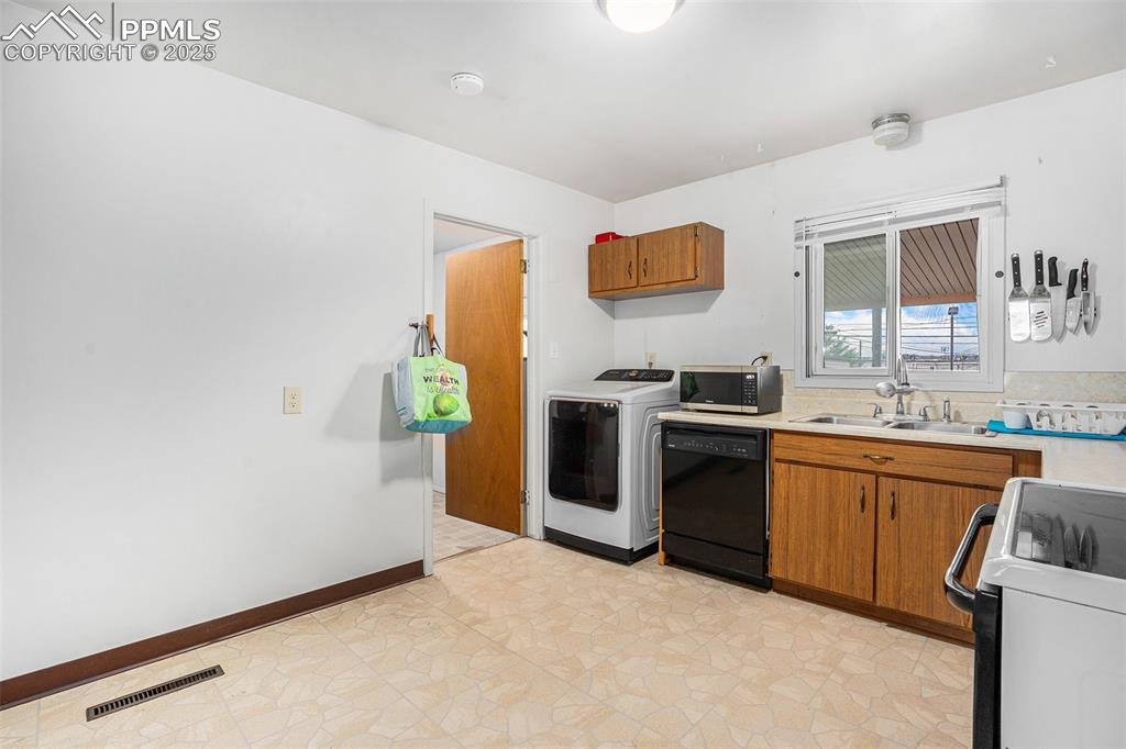 Image 12 of 30: Kitchen featuring range, light countertops, black dishwasher, washer / drye