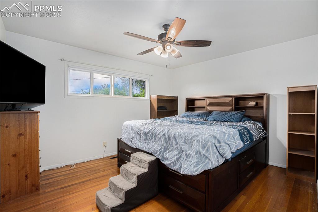 Image 16 of 30: Bedroom with wood finished floors and ceiling fan