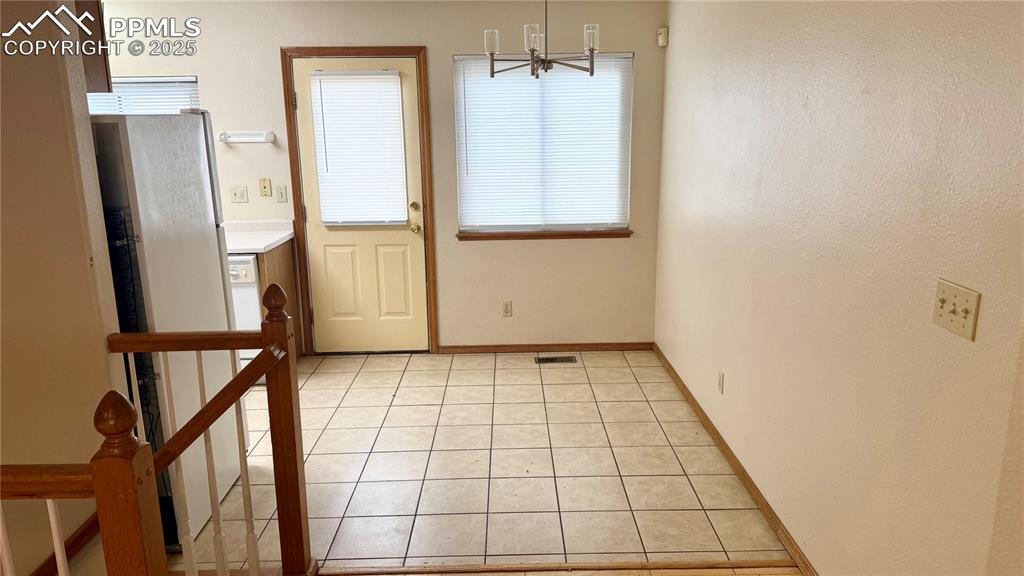 Image 4 of 16: Unfurnished dining area with a chandelier, light tile patterned flooring, a