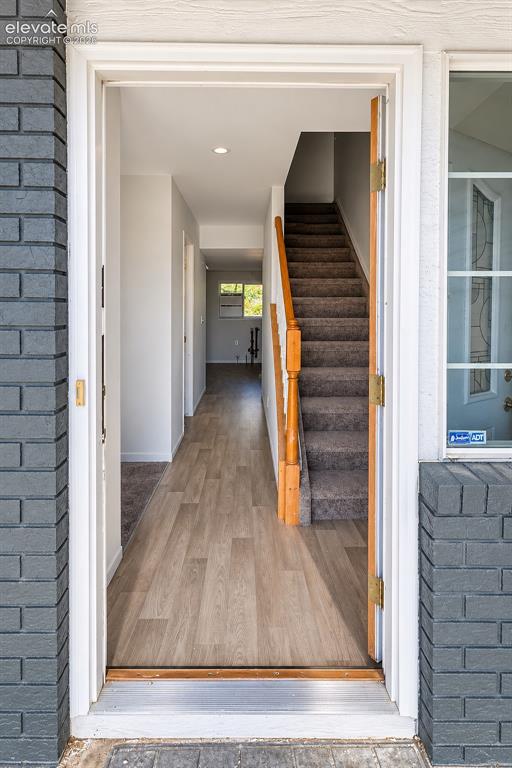 Image 2 of 32: Entryway featuring dark brick exterior siding, light-toned wood-finish floo