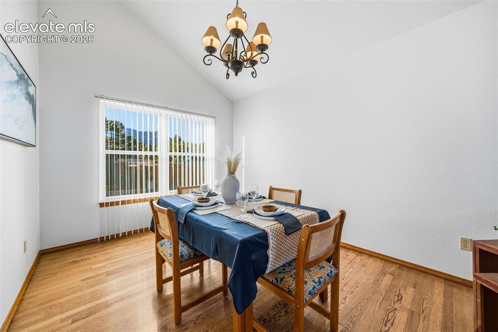 Image 12 of 49: Vaulted ceiling, wood-finish flooring, and multi-light chandelier