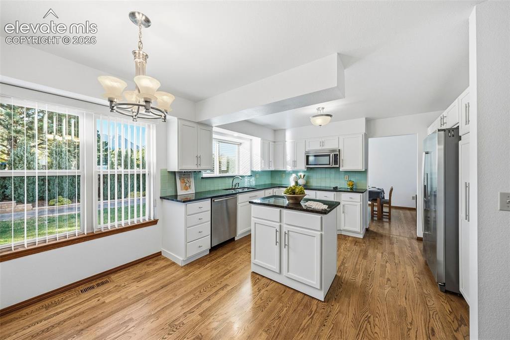 Image 14 of 49: Kitchen featuring white cabinetry, center island, dark stone-finish counter