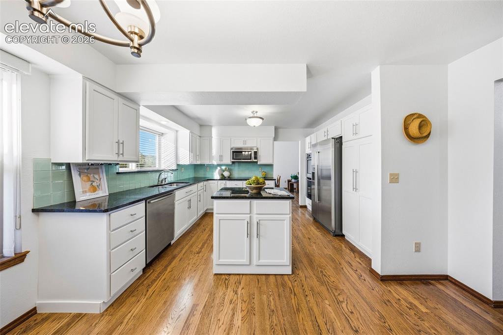 Image 15 of 49: Kitchen featuring white shaker-style cabinetry, dark stone countertops, a c