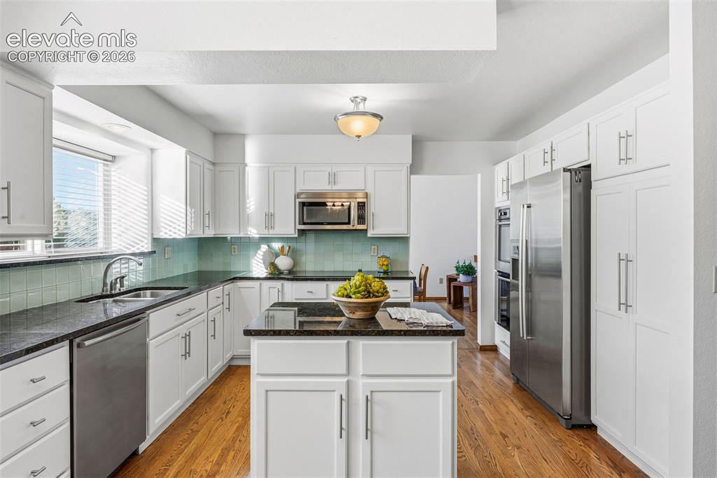 Image 16 of 49: Kitchen featuring white cabinetry with silver-tone hardware, dark stone-fin