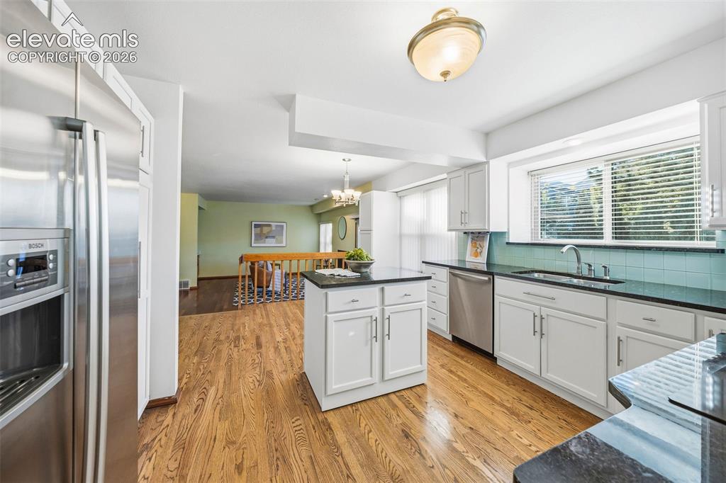 Image 19 of 49: Kitchen featuring white shaker-style cabinetry, dark stone countertops, a c