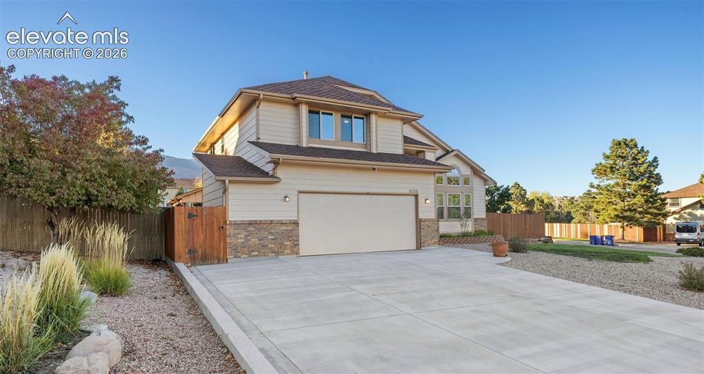 Image 2 of 49: Two-story residence featuring horizontal siding, stone veneer accents, a sh