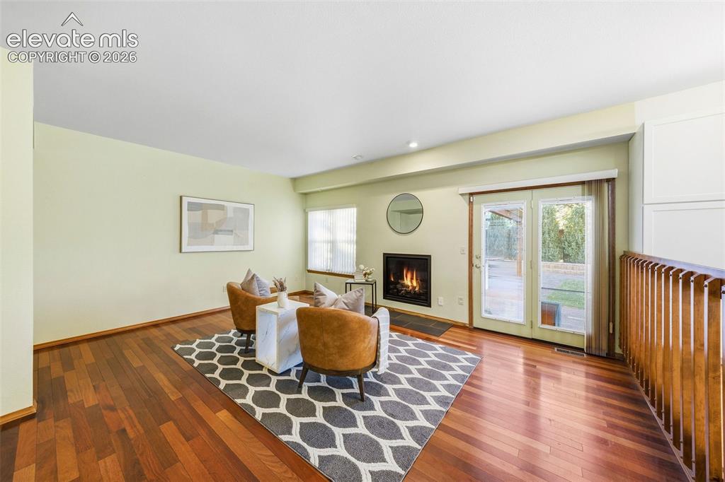 Image 20 of 49: Wood-finish flooring, fireplace with a black surround, and double glass-pan