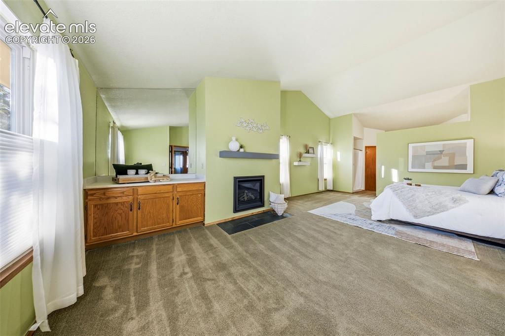 Image 25 of 49: Vaulted ceilings, fireplace with a mantel, built-in cabinetry, mirror-accen