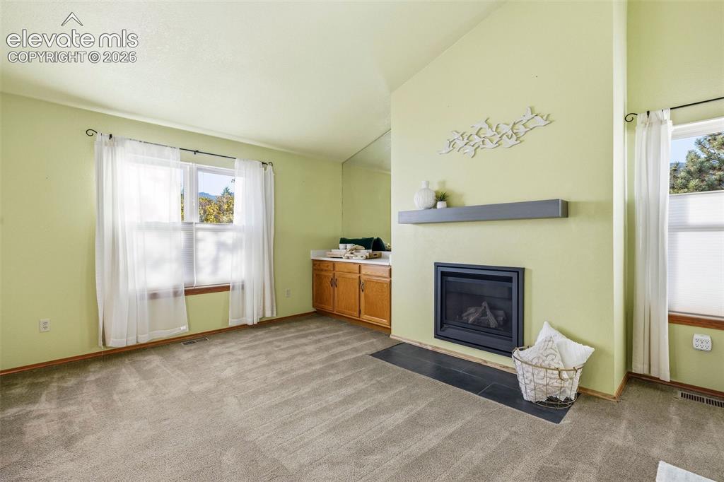 Image 26 of 49: Vaulted ceilings, fireplace with a slate-tile hearth, floating mantel, and