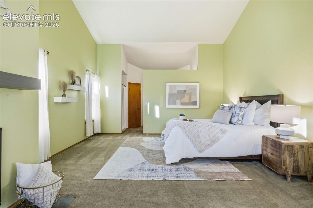 Image 27 of 49: Vaulted ceiling, carpeted flooring, and wall-mounted floating shelves