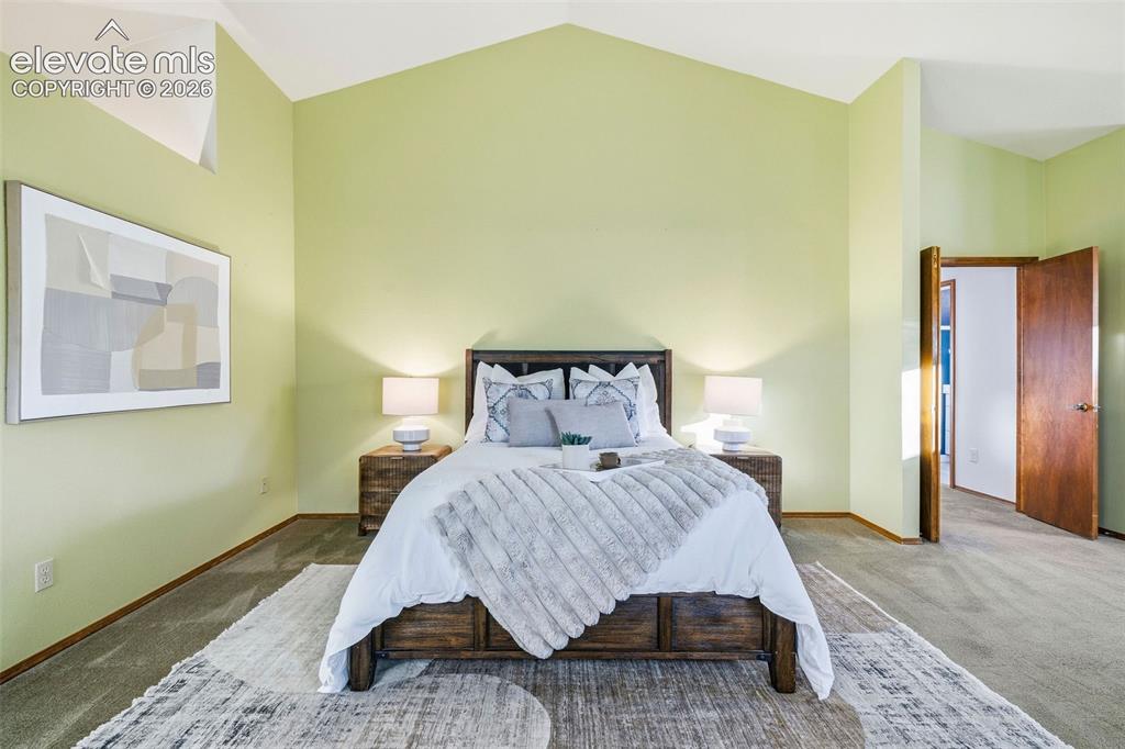 Image 28 of 49: Vaulted ceiling, interior wooden door, and neutral carpeting