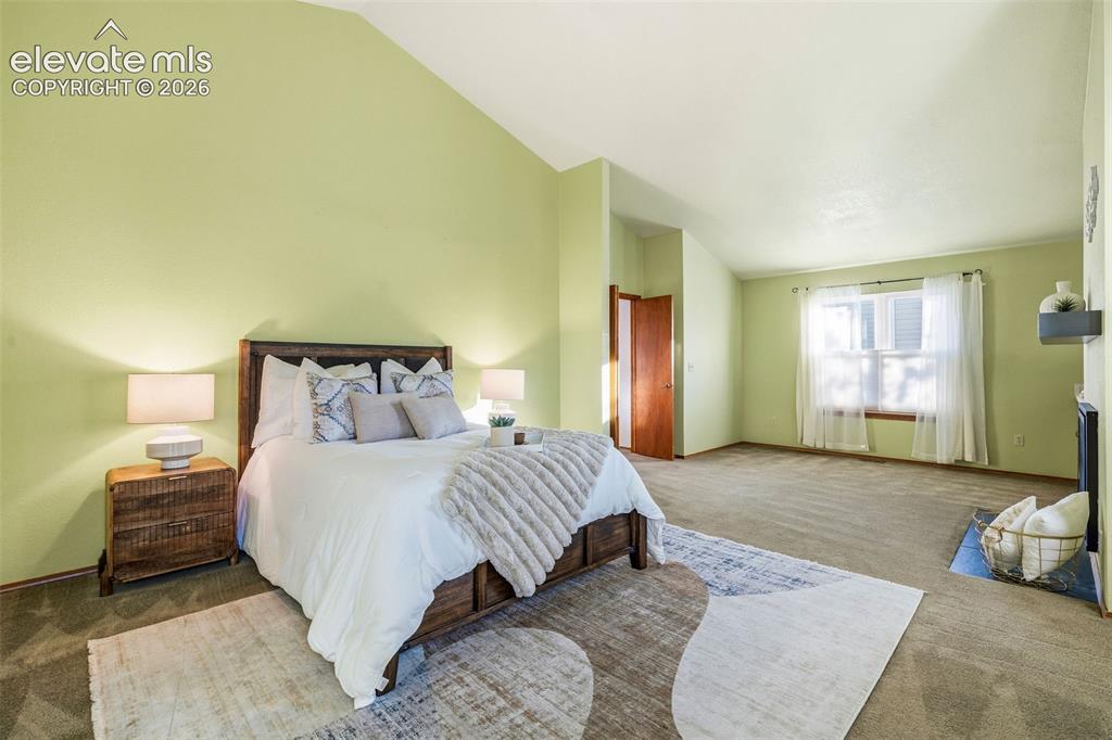 Image 29 of 49: Vaulted ceilings, carpeted flooring, large window with natural light, and a