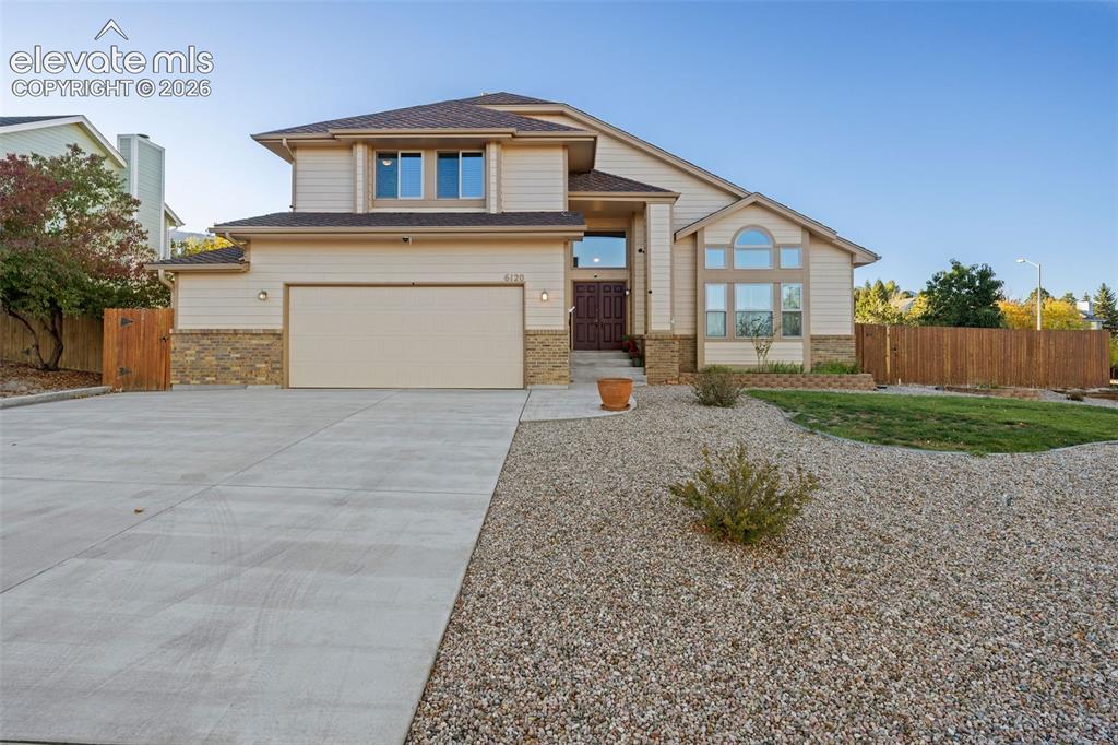 Image 3 of 49: Two-story exterior featuring tan horizontal siding, stone veneer accents, m