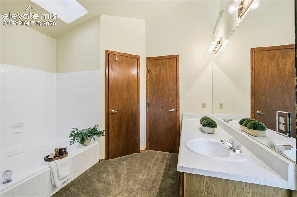 Image 30 of 49: Bathroom featuring a dual-sink vanity with a solid-surface countertop, a so