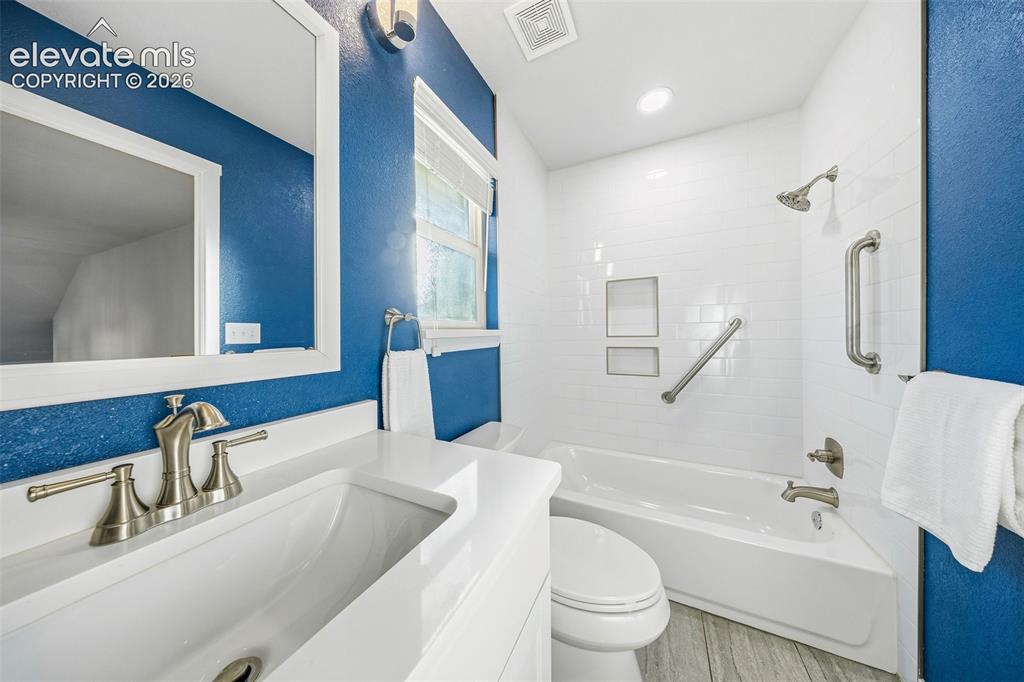 Image 33 of 49: Bathroom featuring a white vanity with a rectangular sink, brushed nickel f