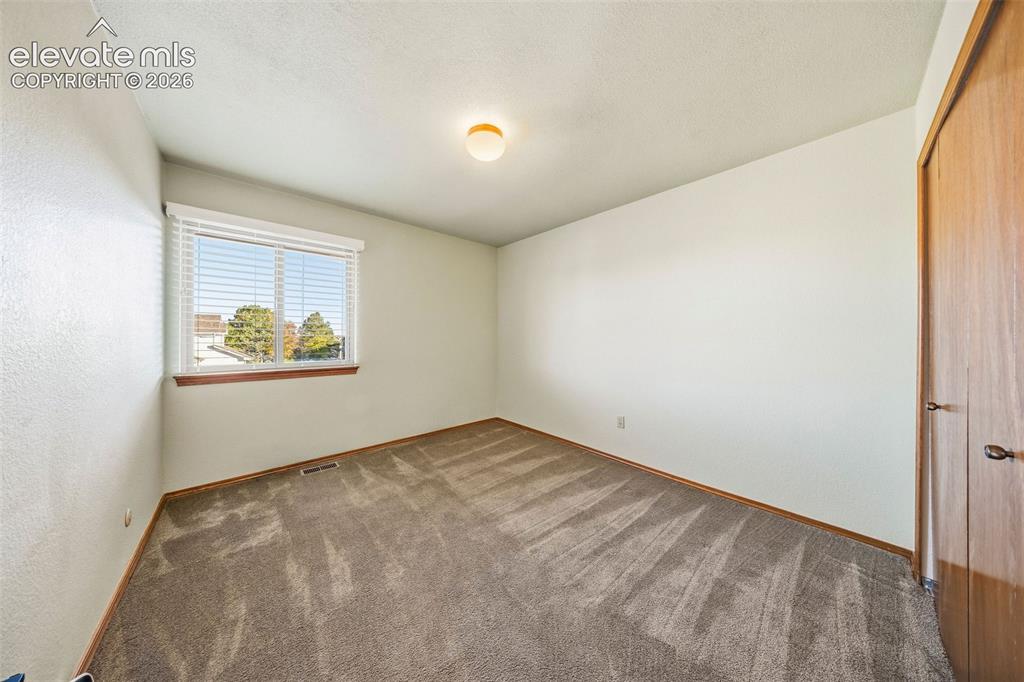 Image 34 of 49: Neutral-toned interior space featuring carpeted flooring, a window with hor