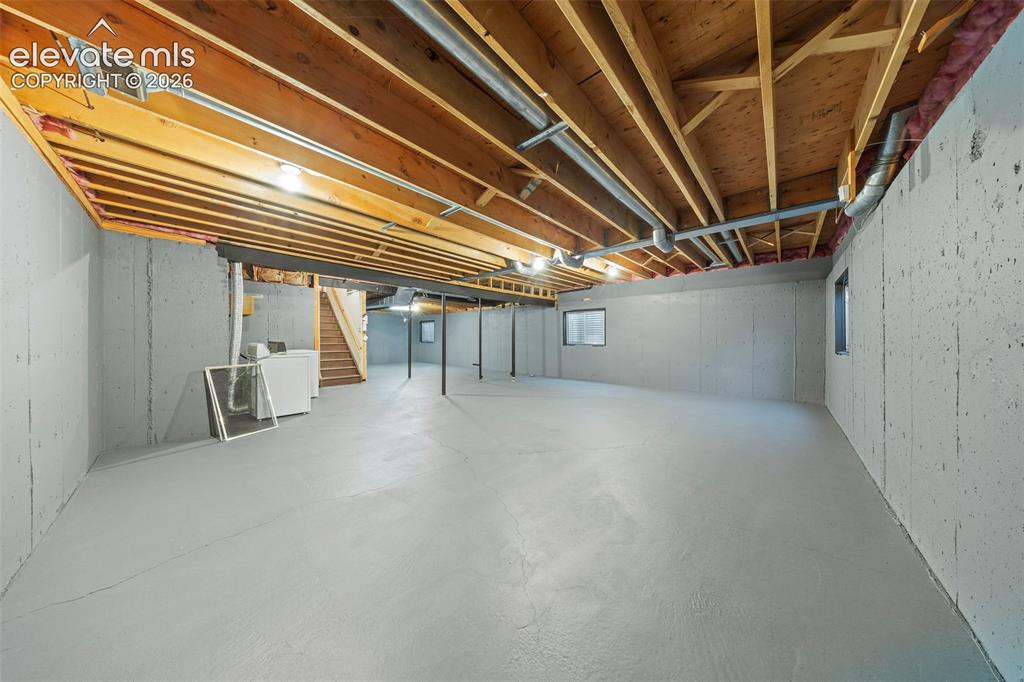 Image 36 of 49: Unfinished lower level featuring exposed wood joist ceilings, poured concre