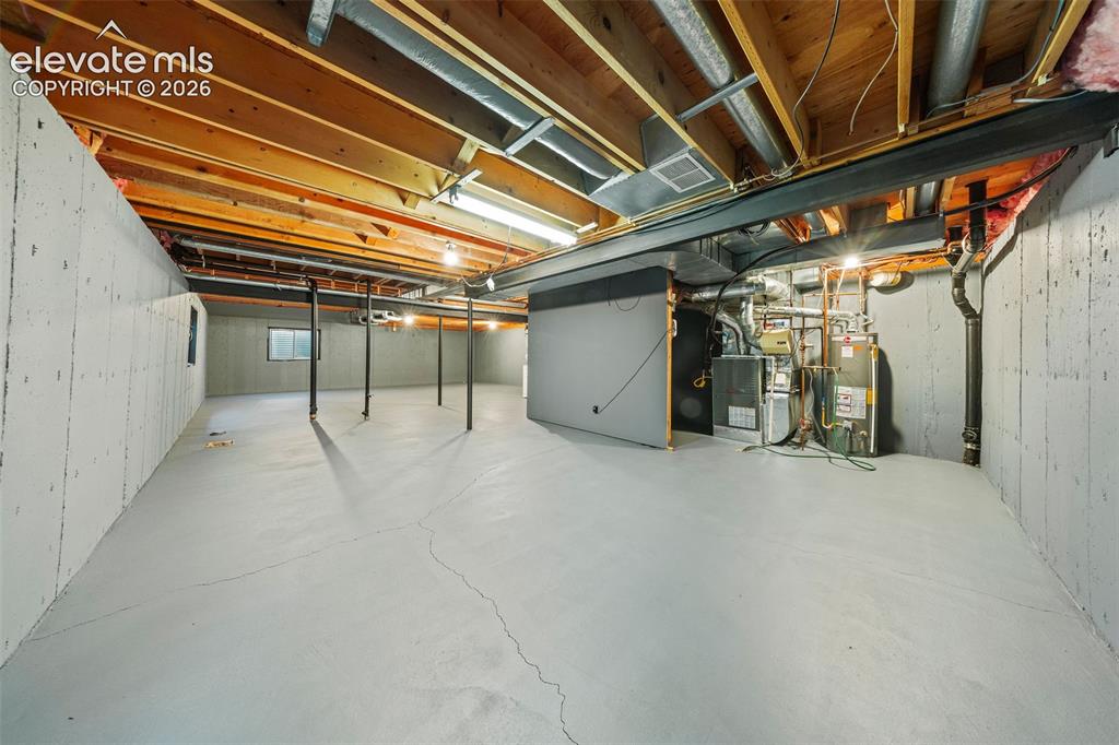 Image 37 of 49: Unfinished lower level featuring exposed wood joist ceilings, painted concr