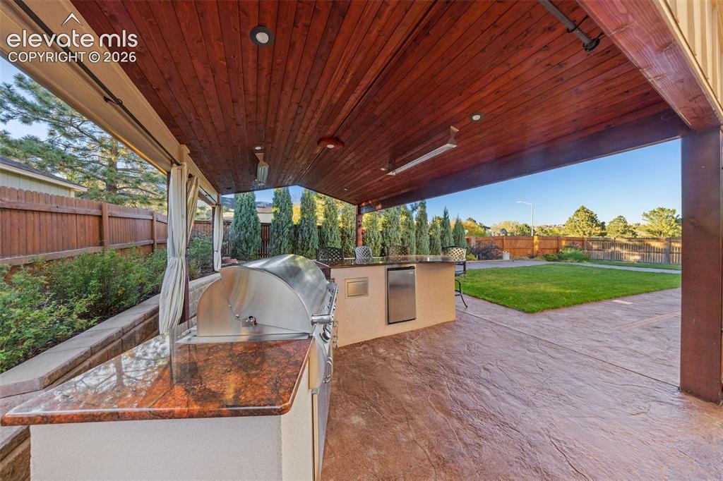 Image 39 of 49: Covered patio featuring a stained wood plank ceiling, stone-textured concre