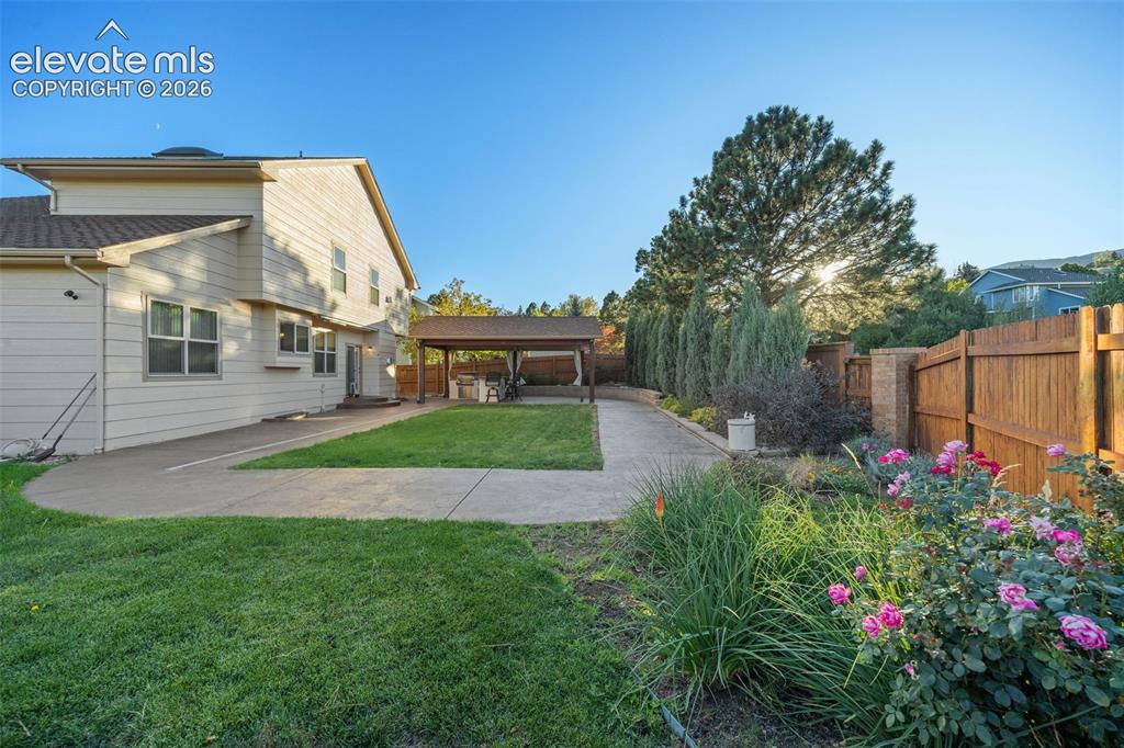 Image 41 of 49: Backyard featuring a concrete patio, covered outdoor pavilion, manicured la