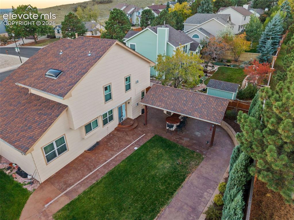 Image 43 of 49: Multi-level exterior featuring a shingled roof with a skylight, covered rea