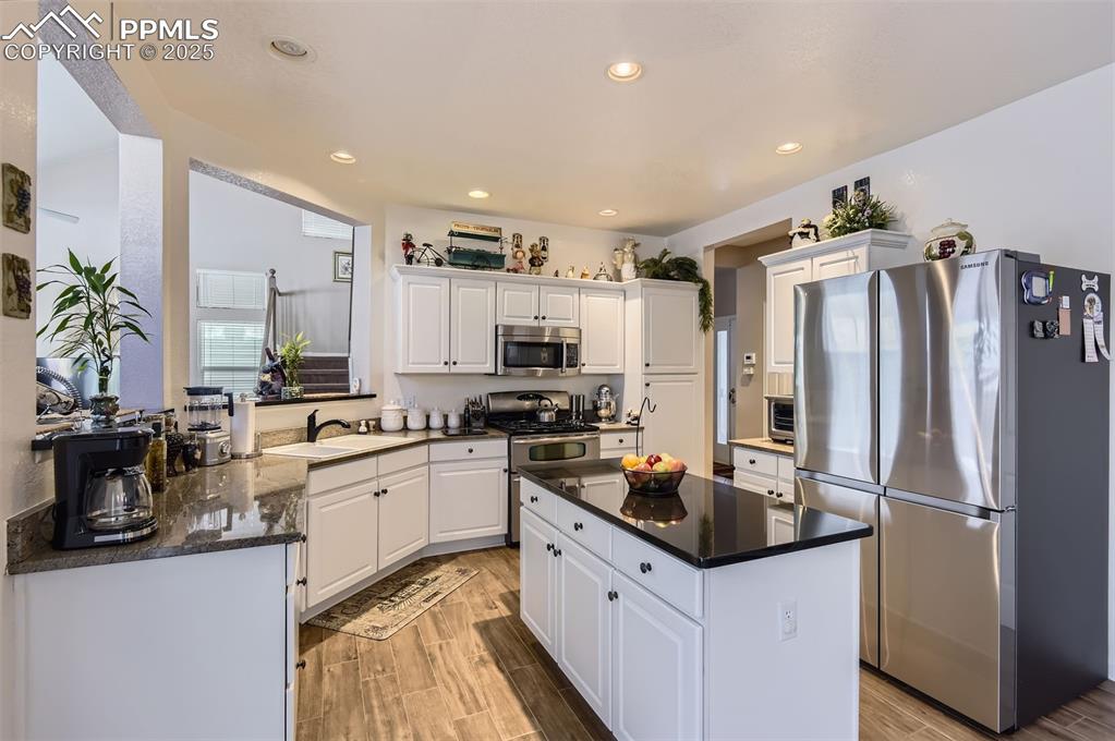 Image 10 of 28: Kitchen featuring appliances with stainless steel finishes, white cabinetry