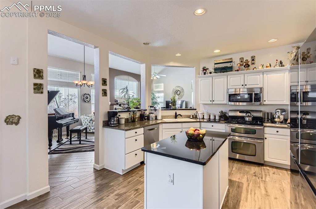 Image 11 of 28: Kitchen with white cabinets, stainless steel appliances, light hardwood / w