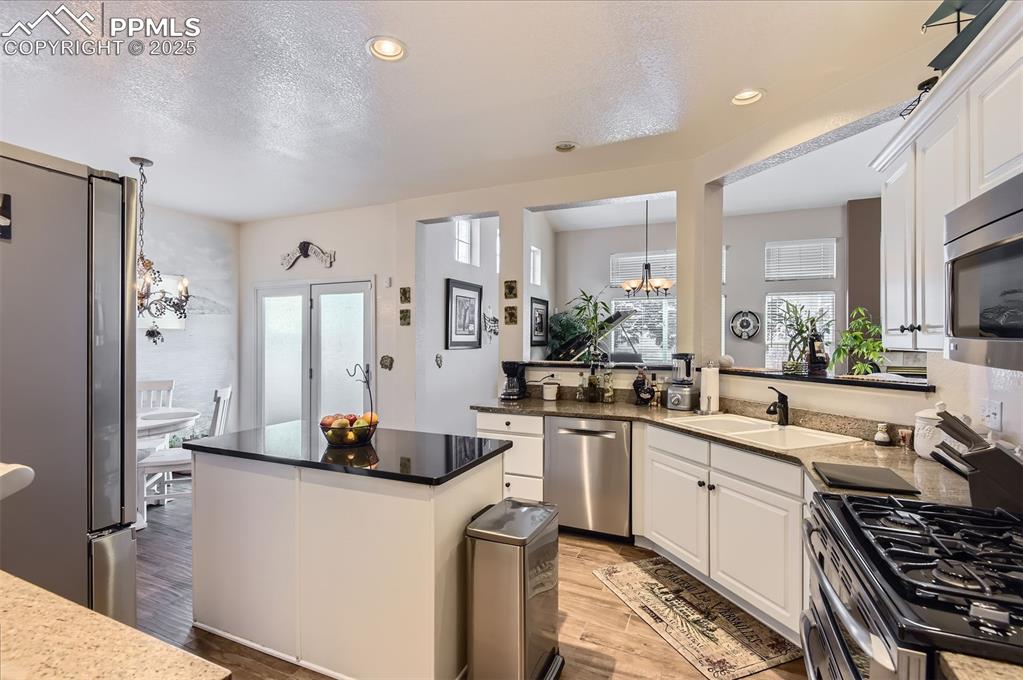 Image 12 of 28: Kitchen with appliances with stainless steel finishes, white cabinets, a te