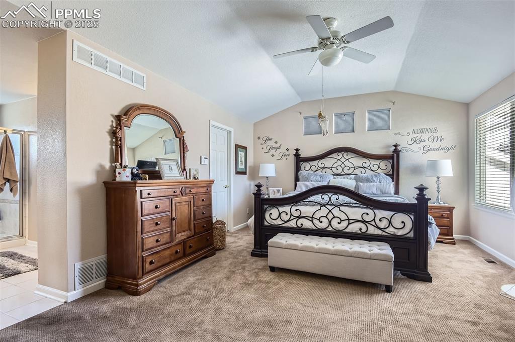 Image 17 of 28: Carpeted bedroom featuring ensuite bath, vaulted ceiling, and ceiling fan