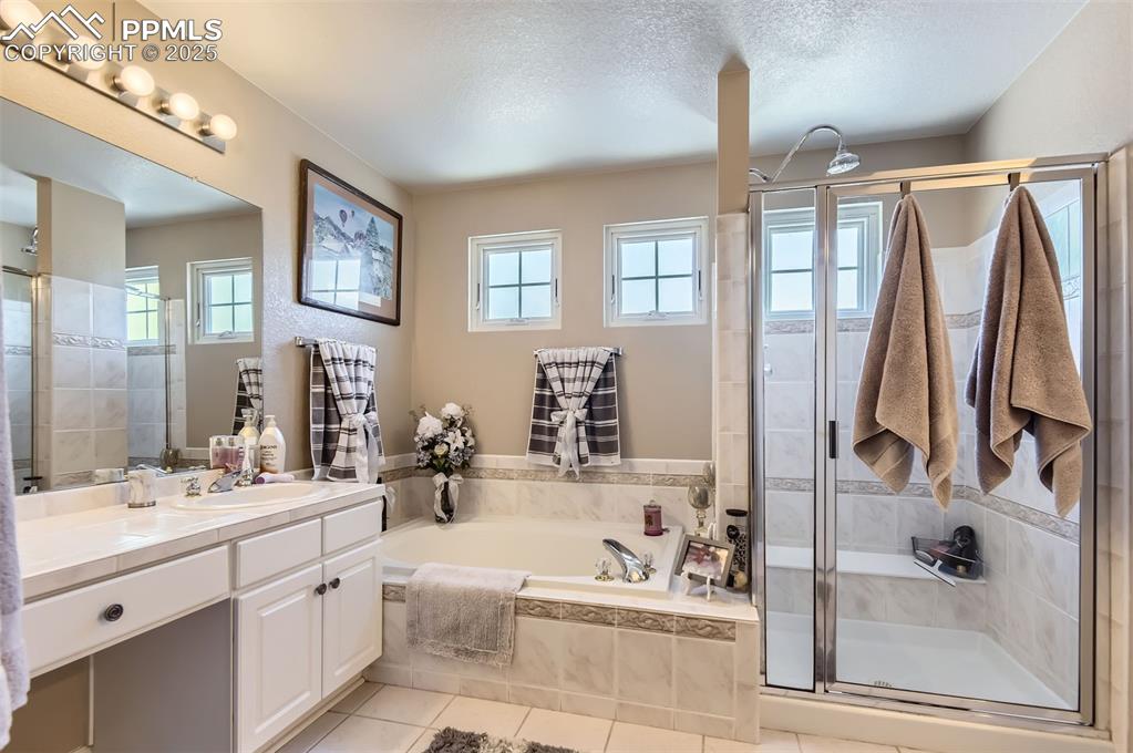 Image 18 of 28: Bathroom with tile patterned floors, a healthy amount of sunlight, a textur