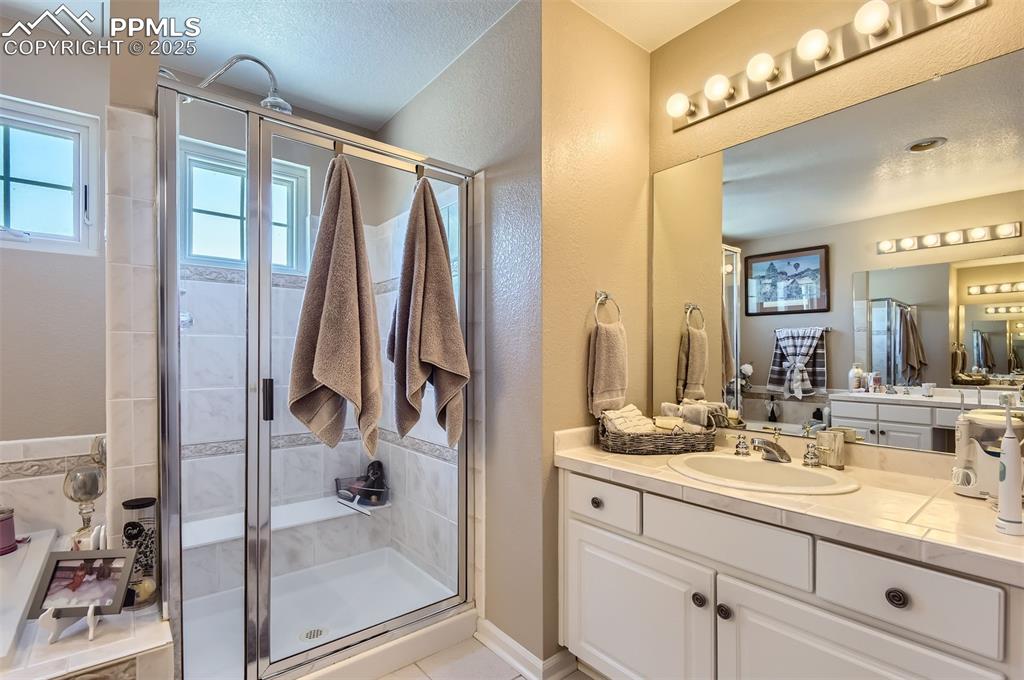 Image 19 of 28: Bathroom featuring a textured ceiling, vanity, tile patterned floors, and a