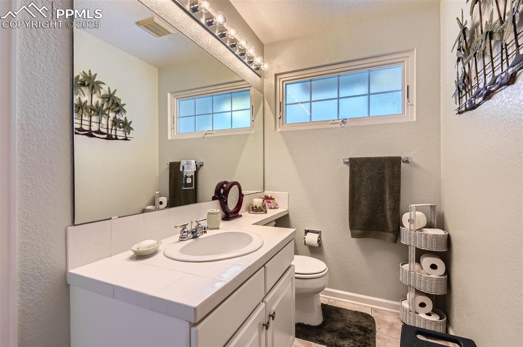 Image 22 of 28: Bathroom featuring toilet, vanity, tile patterned floors, and a healthy amo