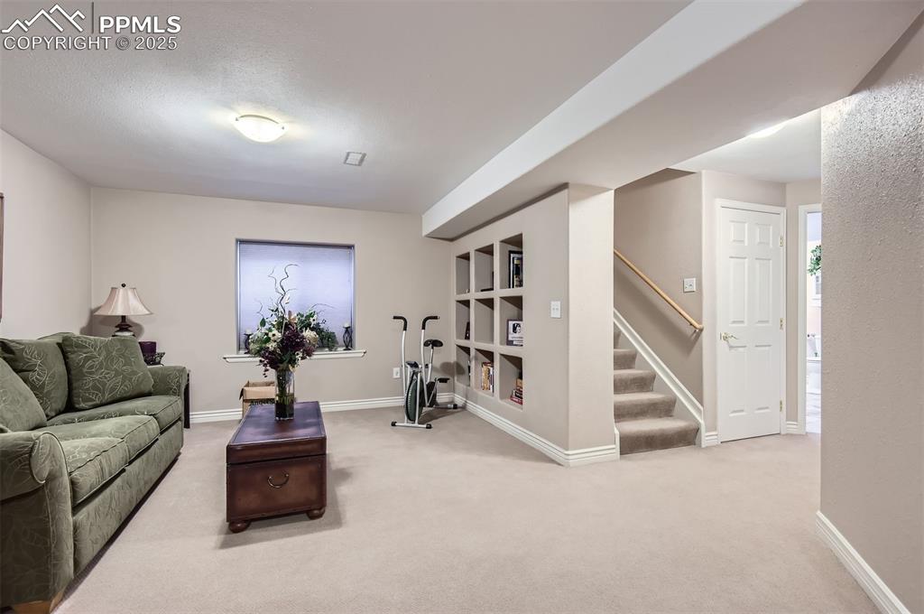 Image 24 of 28: Living room with built in shelves and light colored carpet