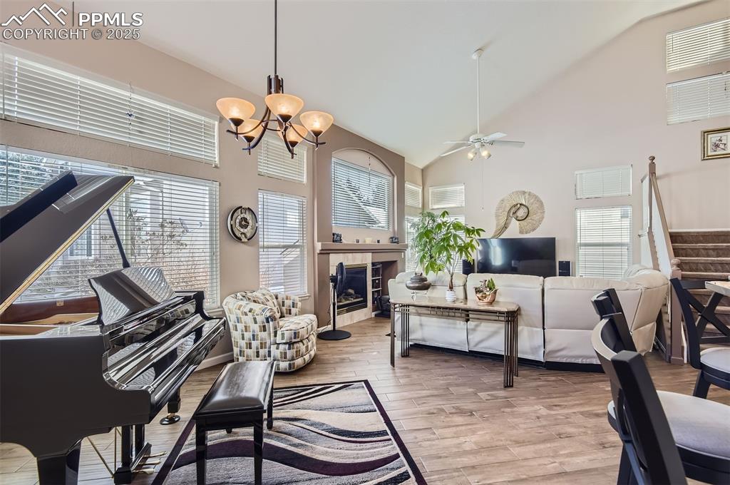 Image 9 of 28: Living room featuring ceiling fan with notable chandelier, light hardwood /